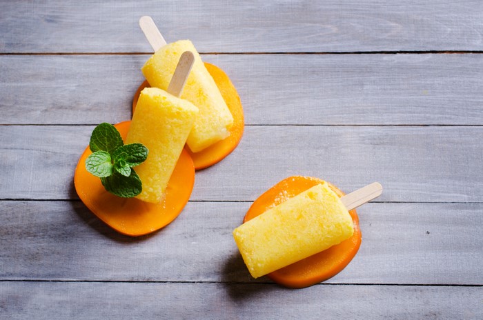 Yellow popsicles on persimmon slices with mint
