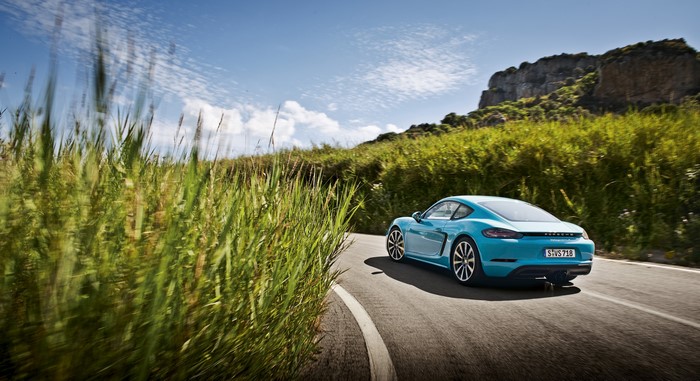 Porsche 718 Cayman driving on a coastal road