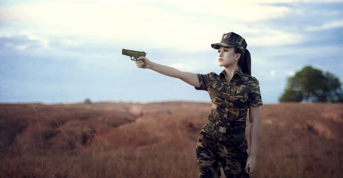 Woman in Camouflage Holding a Pistol
