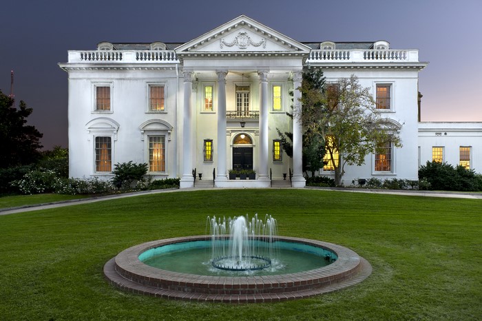 White mansion with columns and fountain on lawn
