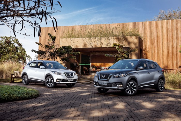 Two Nissan Kicks cars parked outside a modern building