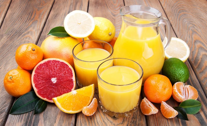 Citrus fruits and juice in glasses and pitcher