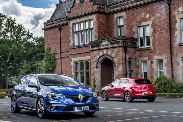 Two Renault Megane cars in front of a brick building
