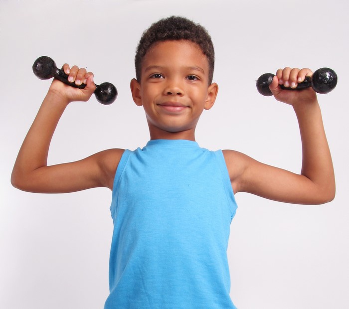 Young boy flexing with dumbbells