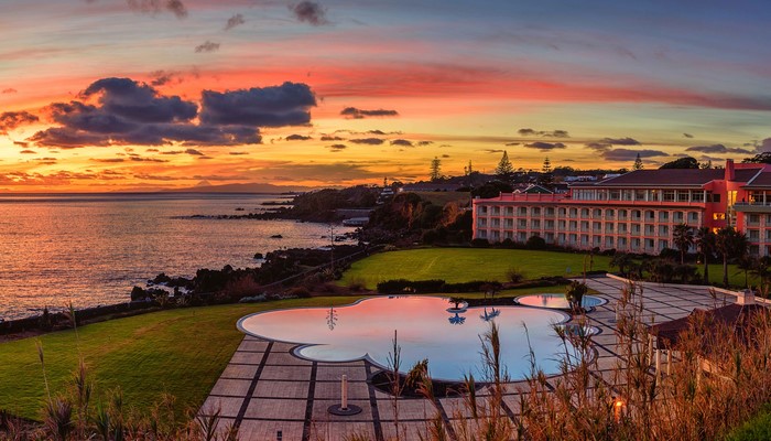 Hotel by the sea at sunset with a swimming pool