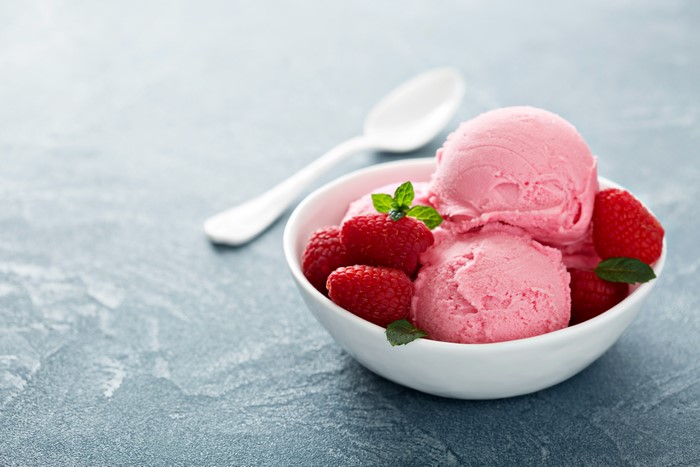 Raspberry ice cream in a bowl with raspberries and mint
