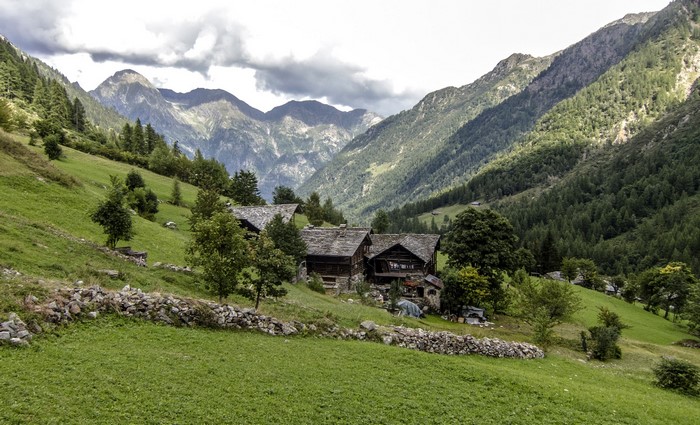 Mountain village with stone houses and green slopes in Italy