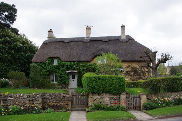 Thatched cottage with stone fence and garden in England