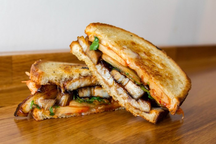 Two halves of a grilled sandwich with meat and vegetables