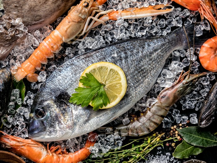 Seafood assortment with fish, shrimp, and lemon on ice