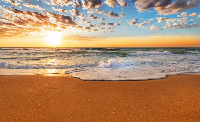 Sunrise over the ocean with waves on the beach