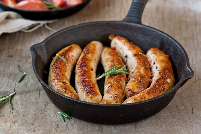 Sausages in a cast iron skillet with rosemary
