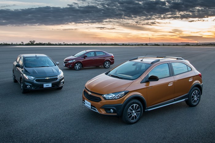 Three Chevrolet cars on asphalt at sunset