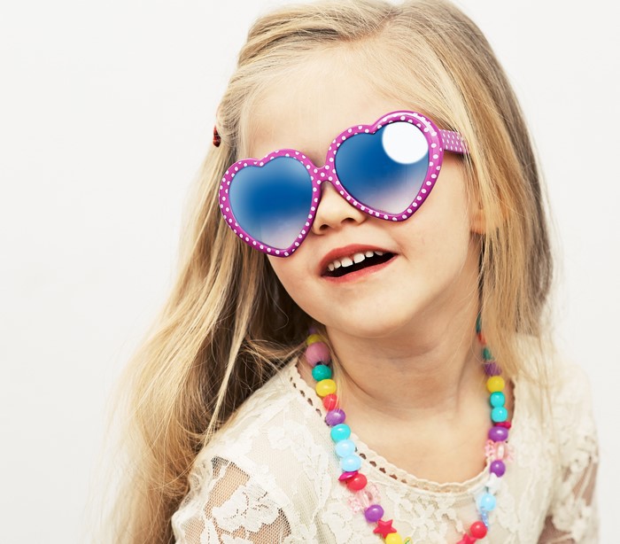 Little girl with heart-shaped glasses and colorful necklace