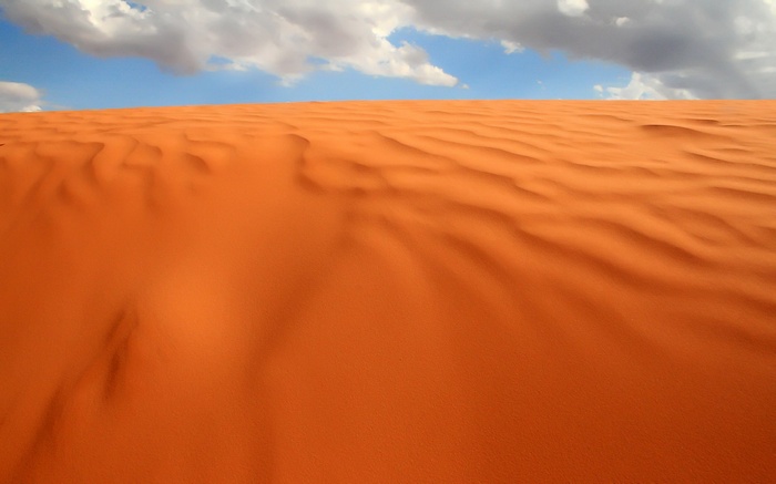Desert sand dunes under a cloudy sky