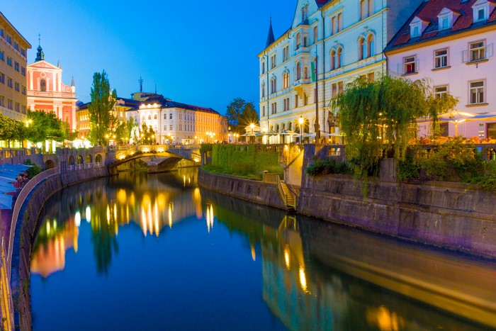 Ljubljana canal at dusk with illuminated buildings