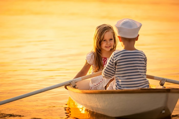 Two children in a rowboat at sunset