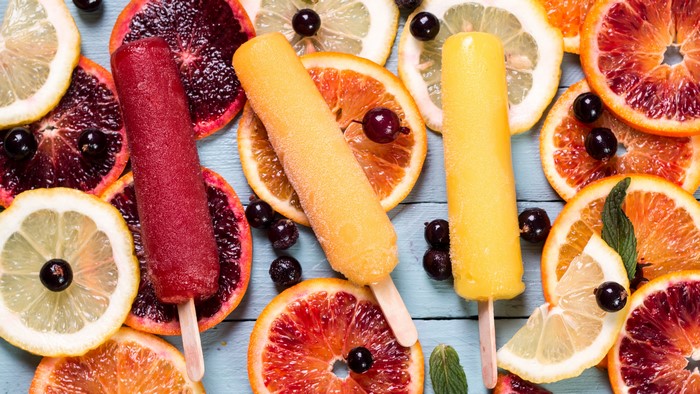 Three popsicles with citrus fruits and berries
