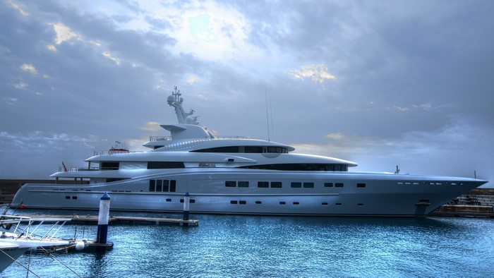 Luxury yacht docked in a harbor under a cloudy sky
