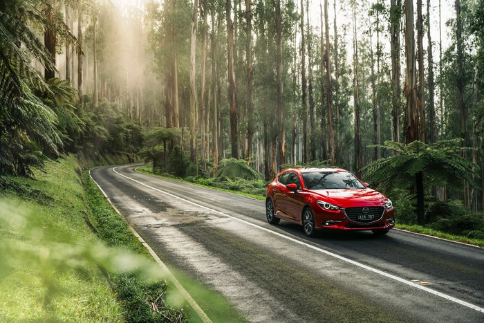 Red Mazda 3 Hatchback on a Forest Road