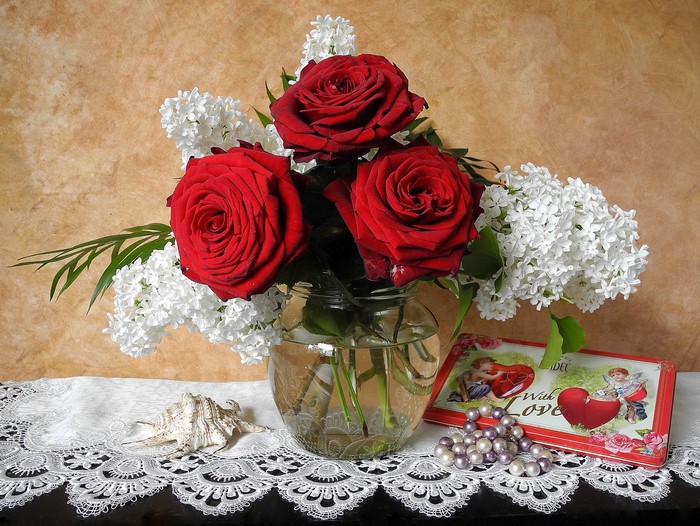 Still-life of red roses and lilac in a vase with jewelry and a box