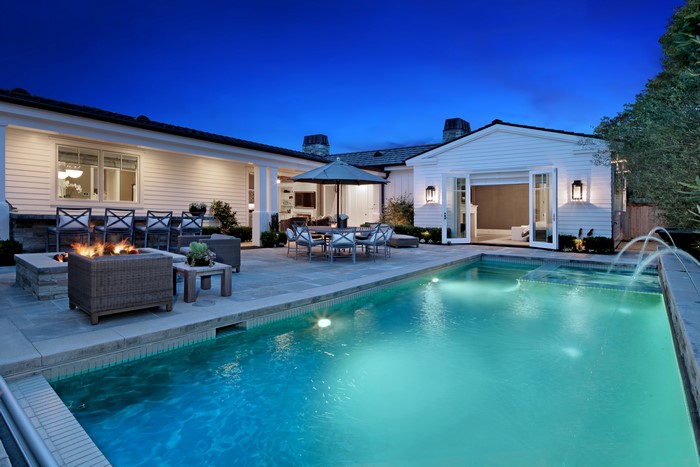 Luxury backyard with pool and fire pit at dusk