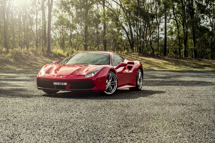 Red Ferrari 488 GTB parked on gravel road