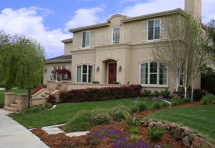 Luxury beige stucco house with manicured landscaping