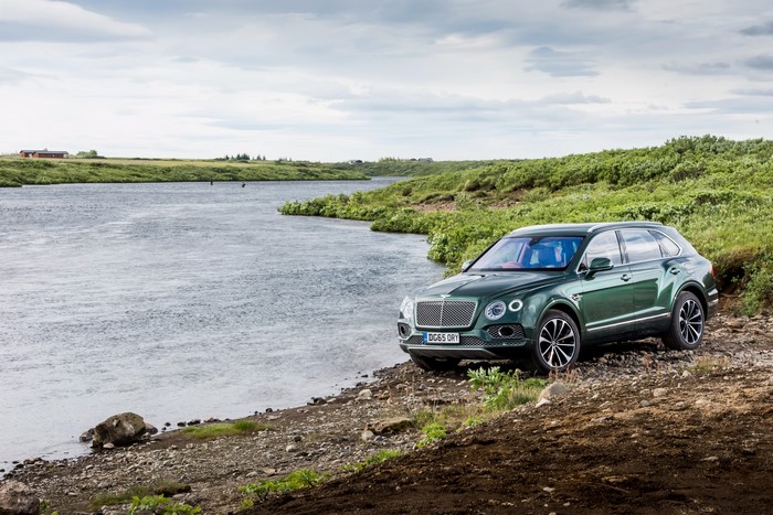 Green Bentley Bentayga SUV parked by a river