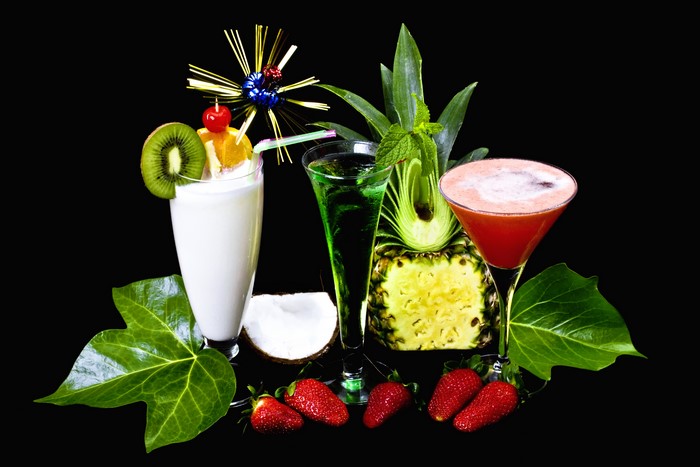 Three cocktails with fruits and foliage on black background