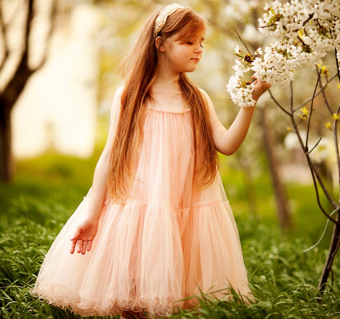 Girl in a pink dress smelling flowers
