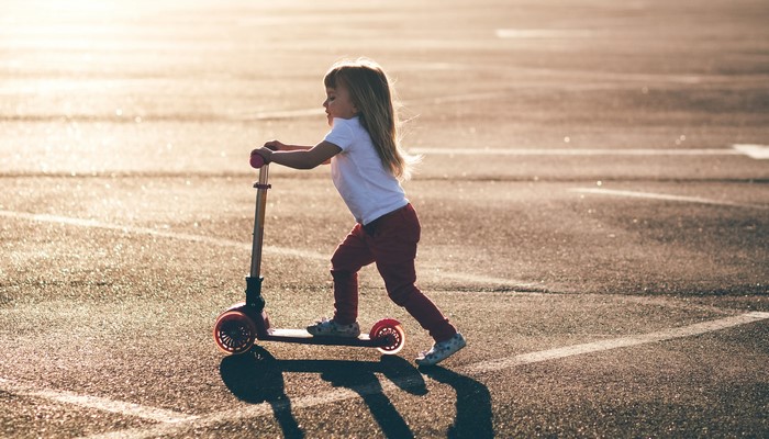 Girl riding a scooter on asphalt