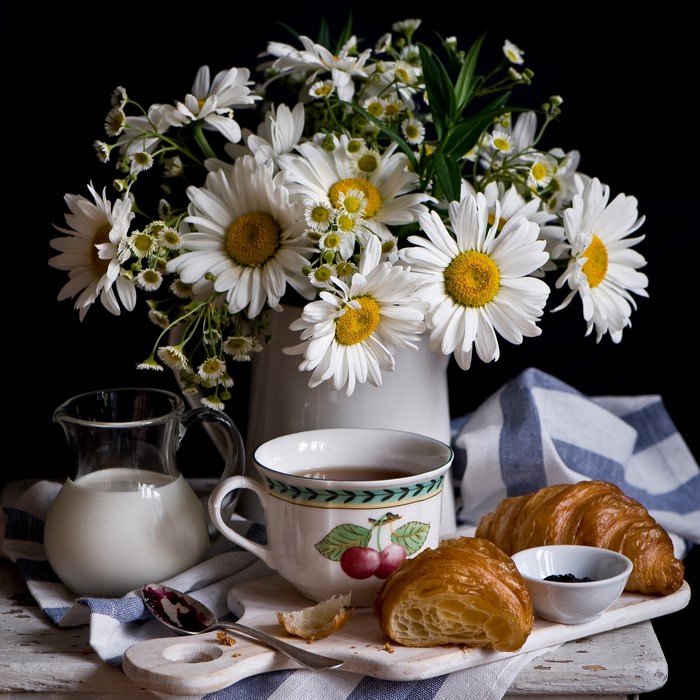 Still life with camomiles, croissants, tea, and milk