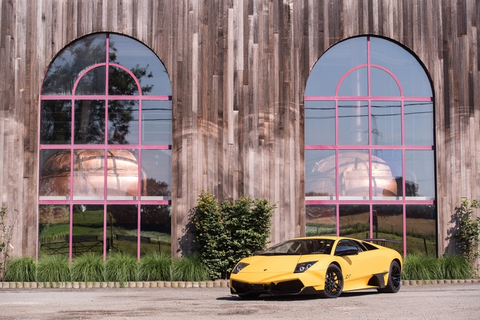 Yellow Lamborghini in front of a wooden building with arched windows