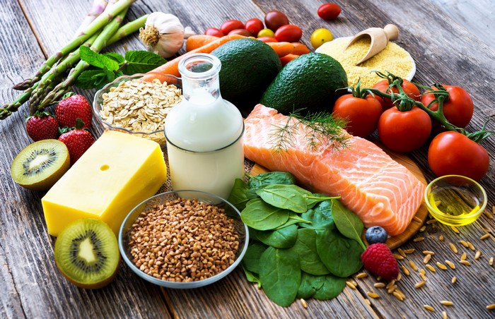 Still life of healthy foods including salmon, vegetables, fruits, and dairy