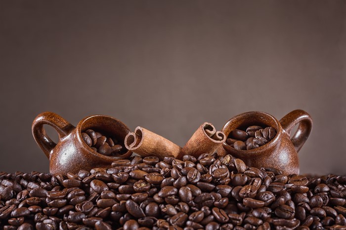 Coffee beans and cinnamon sticks in cups
