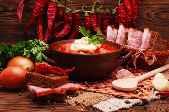 Borscht soup with sour cream, bacon, bread, and chili peppers