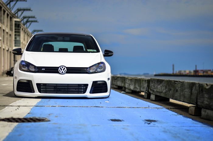 White Volkswagen Golf R parked by a pier