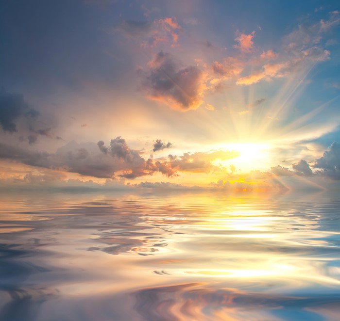 Sunset over the ocean with clouds and sun rays
