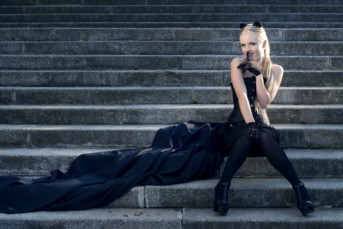 Blonde girl in black outfit sitting on stone stairs