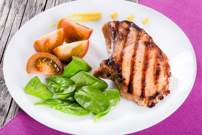 Grilled pork chop with tomatoes and spinach
