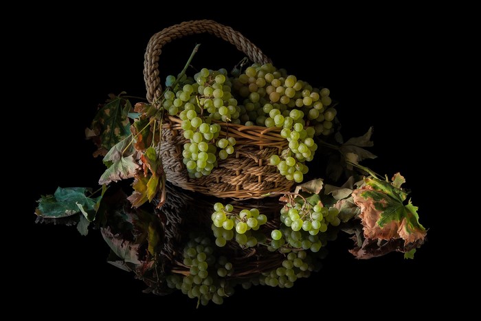 Green grapes in a wicker basket with leaves