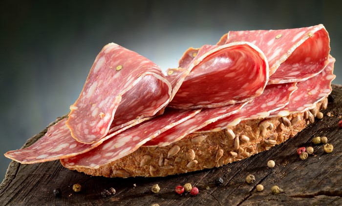 Slices of salami on a rustic bread with peppercorns