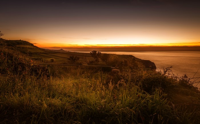 Sunset over the coast with grass and fields