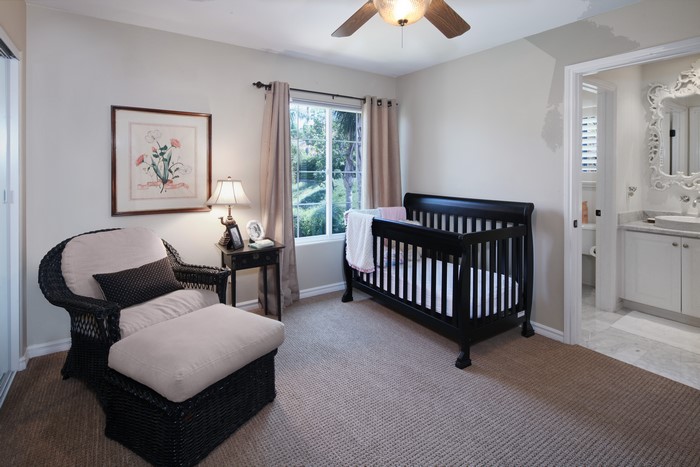 Nursery with crib, armchair, and adjoining bathroom
