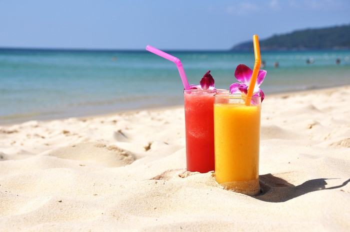 Two tropical drinks on a sandy beach