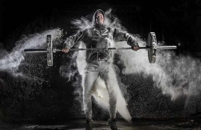 Man lifting barbell with powder explosion