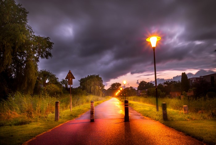 Road at night with street lights and stormy sky