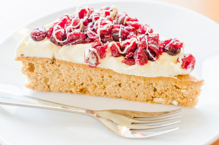 Slice of cake with cranberries and cream