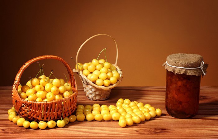 Yellow cherries in baskets and a jar of jam